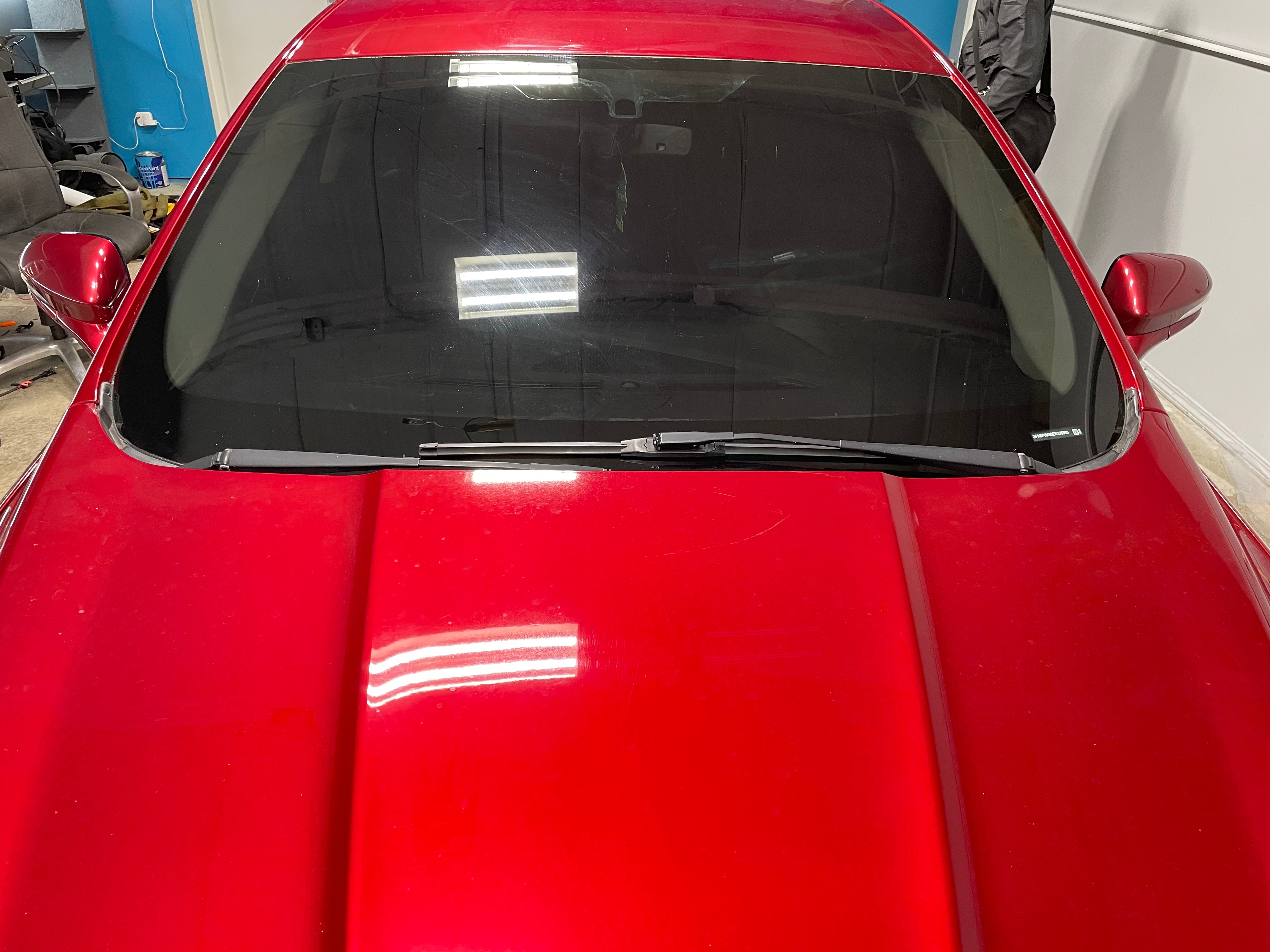 alt="Red sedan with full front windshield tint for heat and UV protection"
