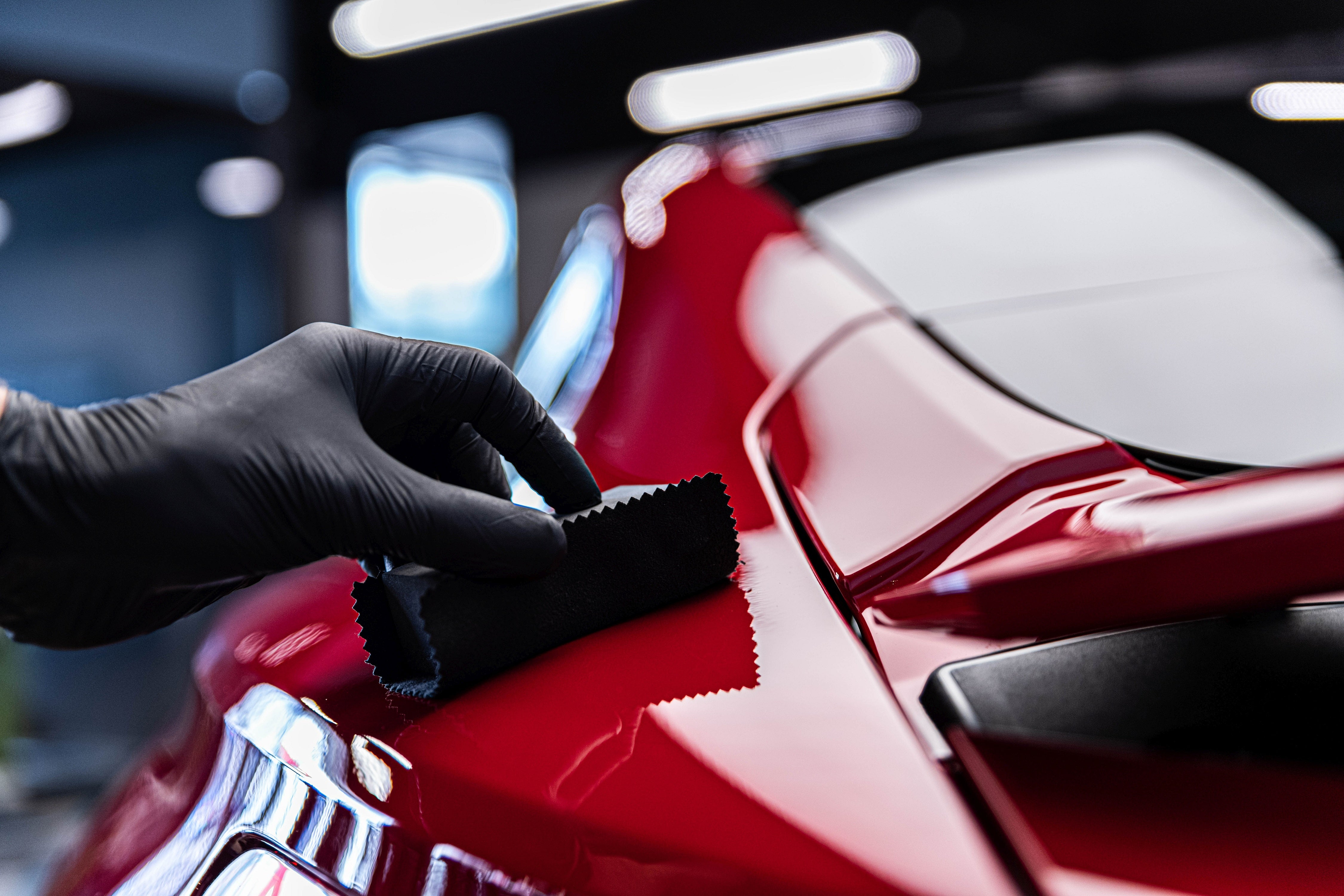 Installing ceramic coating on red sports car