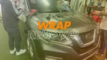 alt="Technician performing full vinyl wrap removal on a black sports car"